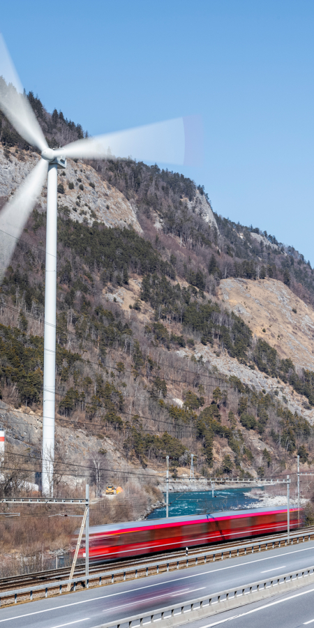© Marke graubünden / Gaudenz Danuser Windrad, Rhätische Bahn und Autobahn in der Umgebung von Chur, die eine nachhaltige Infrastruktur repräsentieren